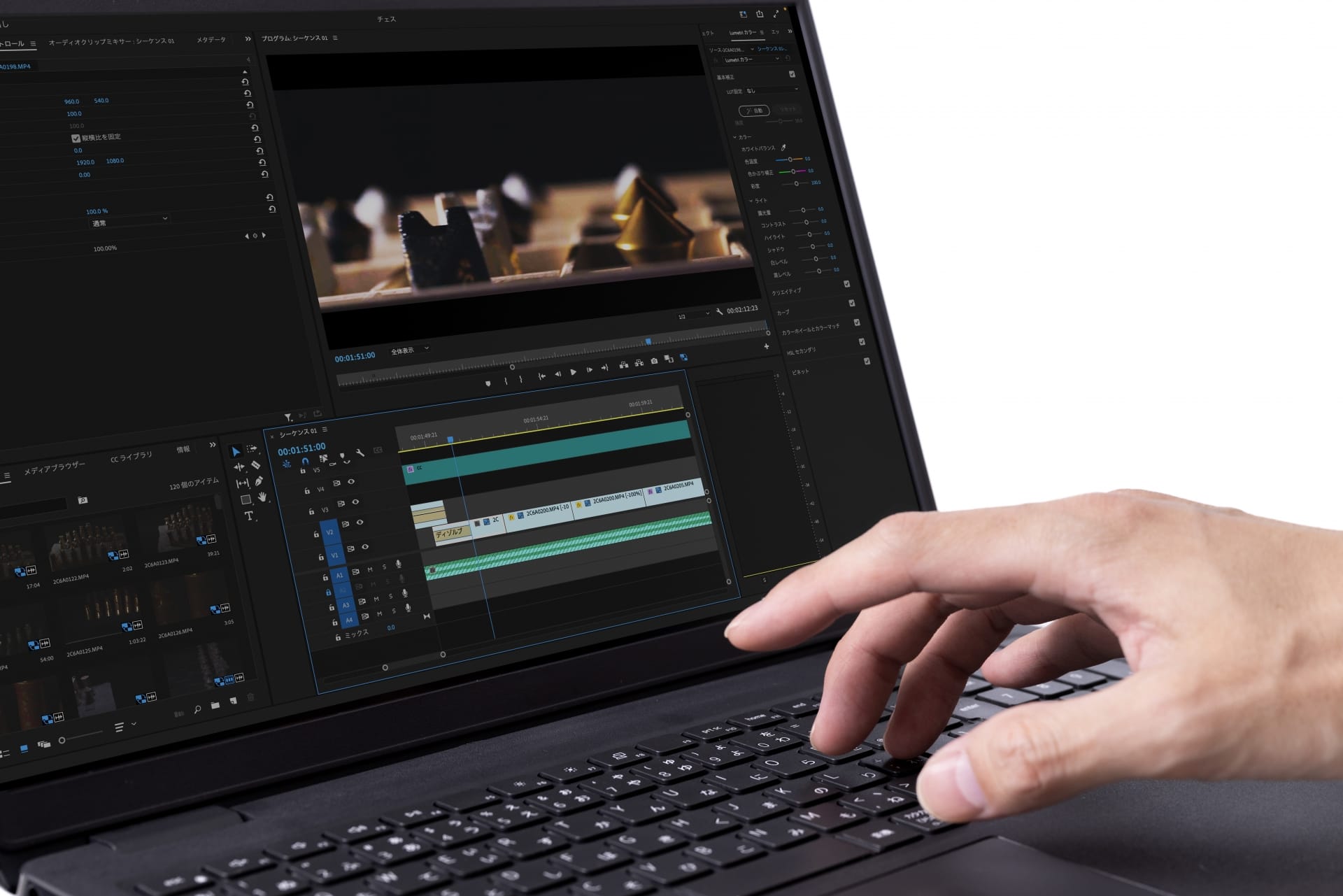 Person edits video on a laptop, with multiple timelines and editing panels visible on screen, hand on keyboard